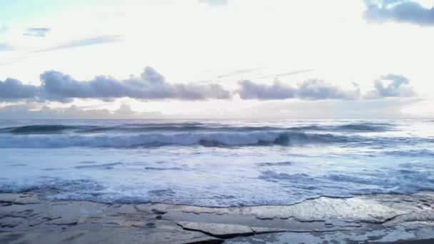 Ondas do mar a cair na praia rochosa. Céu nublado dramático sobre o oceano tempestuoso — Vídeo de Stock