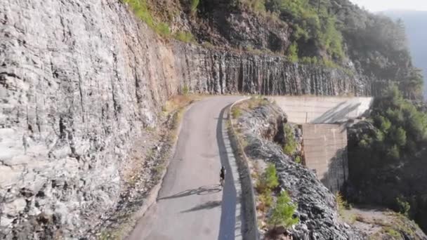 Female athlete cyclist climbing up difficult climb. Cyclist on bicycle riding on road in mountains — Stock Video