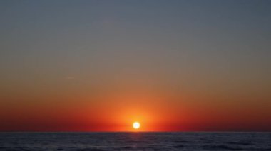 Deniz dalgaları üzerinde gün batımı. İnanılmaz turuncu gün doğumu. Güneş ışığı su yüzeyine yansıyor