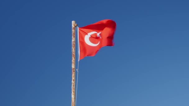 Turkiet flagga smickrande på vinden mot blå himmel. Röd turkisk flagga viftar på flaggstången — Stockvideo