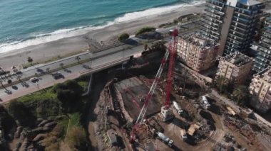Deniz kıyısına yakın bir otel inşaatı. Kule vinci, kazıcı ve makineli inşaat alanı