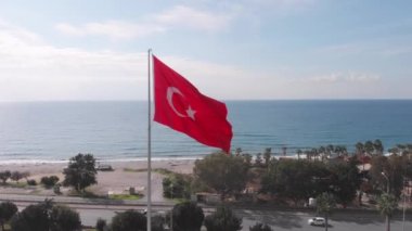 Türkiye 'nin ulusal bayrağı mavi gökyüzüne karşı rüzgarda dalgalanıyor. Bayrak direğinde Türk bayrağı