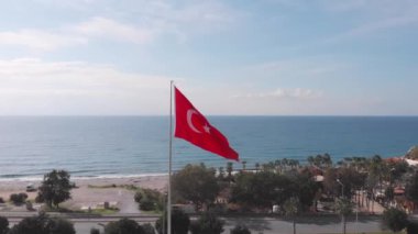 Mavi gökyüzüne karşı rüzgarda dalgalanan beyaz yıldızlı Türk bayrağı