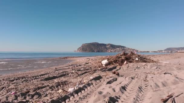 Schmutziger Strand der Stadt Alanya nach starkem Sturm. Müll und Baumschutt liegen am Sandstrand — Stockvideo