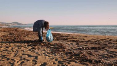 Plajda bırakılmış plastik şişeleri toplamaya gönüllü biri. Plajı temiz tutuyor.