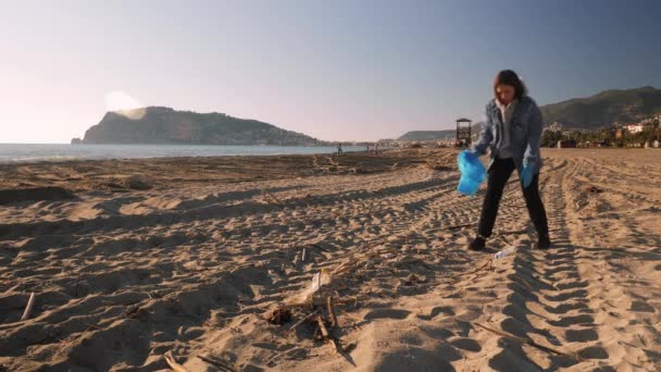 Žena sbírající plastové odpadky na pláži. Dívka čištění pláže z plastových lahví a koše — Stock video