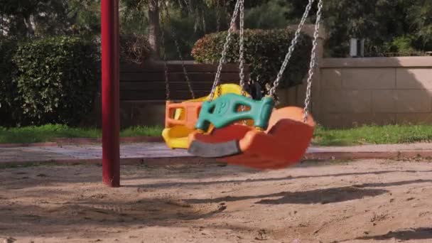 Huśtawki na pustych dzieciach lub placu zabaw. Kolorowe huśtawki z metalowymi łańcuchami — Wideo stockowe