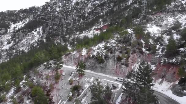 Coche conduciendo a través de carretera de cambio de bobinado escénico corriendo a través de madera verde idílico y montañas nevadas — Vídeos de Stock