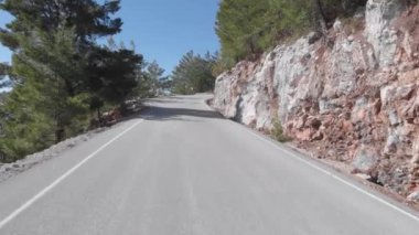 Kayalık tepeler ve yeşil orman boyunca uzanan boş dağ yolu. Kırsalda seyahat etmek