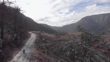 Bisikletçi yanan dağ ormanında bisiklet sürüyor. Profesyonel atlet bisiklet ve yol bisikleti eğitimi