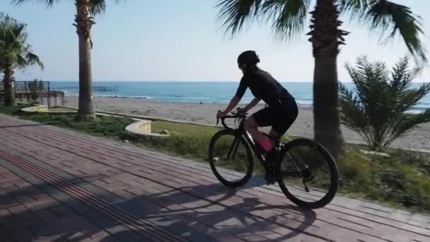 Cycliste promenades vélo de route à travers les palmiers sur la promenade de la plage de sable fin. Femme vélo à vélo à la journée ensoleillée d'été — Video