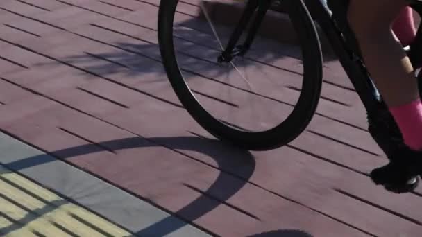 Ruota bici rotazione al tramonto, da vicino. Gambe del ciclista in sella alla bicicletta su strada sul lungomare — Video Stock