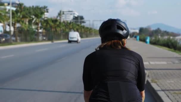 Yazın güneşli bir günde bisiklet süren bir bisikletçi. Kasklı ve bisikletli bir kadın dışarıda bisiklet sürüyor. — Stok video