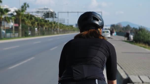 Güneşli yaz gününde şehir caddesinde bisiklet süren bir kadın. Bisiklet ve triatlon konsepti — Stok video