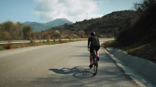 자전거를 타는 프로 도로 자전거 선수. 오토바이를 타고 산길을 달리는 여자 — 비디오