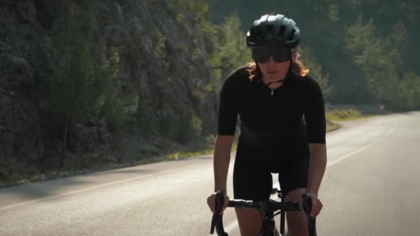 Интенсивная велосипедная тренировка. Профессиональная женщина-велосипедистка ускоряется на велосипеде на горном холме — стоковое видео