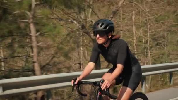 Adatto a ciclista professionista atletico in bicicletta su strada. Affascinante atleta donna in sella alla bicicletta al sole — Video Stock