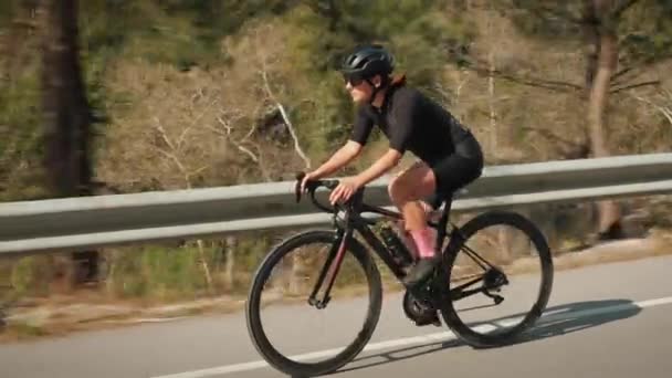Profesionální cyklista jezdící na sportovním kole do kopce v lese. Sportovec na dlouhé rovné silnici v horách — Stock video