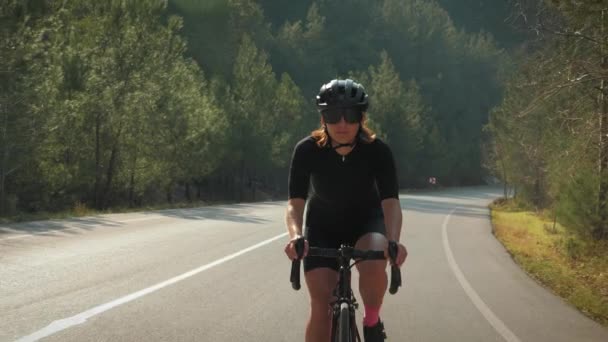 Profesionální cyklista na kole šplhá na strmý kopec. Přizpůsobit atletická žena atlet tvrdý trénink na silniční kolo — Stock video