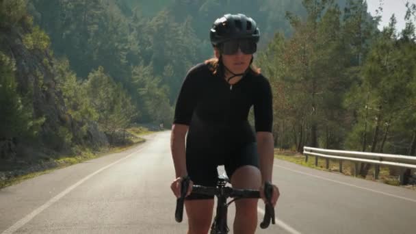 Женщина-велосипедистка на велосипеде. Профессиональные велосипедисты тренируются на дорожном велосипеде, поднимаются в гору. Дорожный велоспорт на горном перевале на закате — стоковое видео