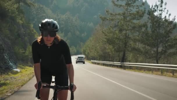 Dağ yoluna tırmanan profesyonel bisikletçi. Bisiklet üzerinde sıkı çalışan kadın sporcu, yoğun kardiyo egzersizi yapıyor. — Stok video