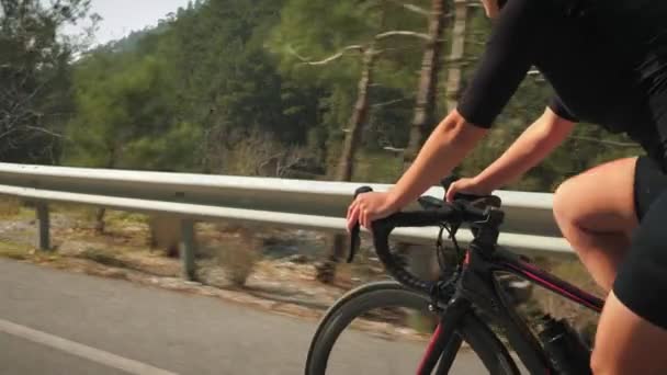 Andar de bicicleta de estrada lá fora. Rotação de roda de bicicleta. Mulher ciclista andar de bicicleta na estrada da montanha — Vídeo de Stock