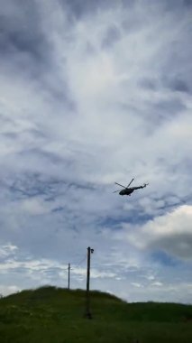 Yeşil çayır üzerinde uçan askeri helikopter. Ukrayna 'da savaş. Dikey video