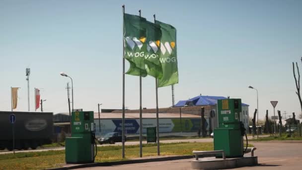 Posto de gasolina para reabastecimento de tanques de automóveis com bandeiras verdes acenando no vento — Vídeo de Stock