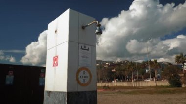 Açık sahil duşu. Sahildeki açık hava duşundan akan su mavi gökyüzüne karşı.