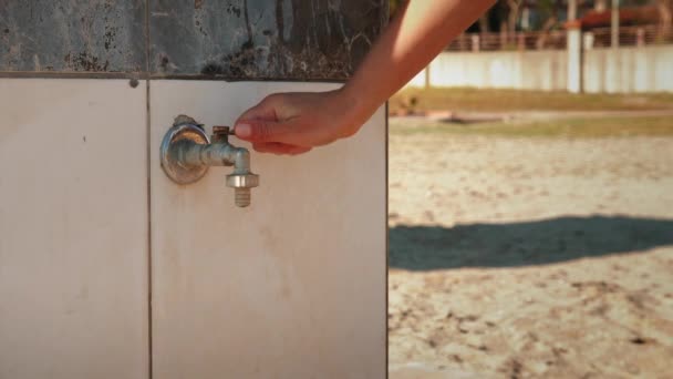Woman washing hands in open shower on beach. Female hands opening shower faucet — Stock Video