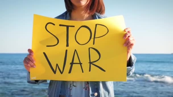 Niña levantando pancarta amarilla Stop War, protestando contra la guerra en Ucrania 2022 — Vídeos de Stock