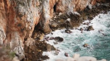 Kristal berrak deniz dalgaları kayalık kıyılara çarpıyor. Kayalık kayalıklar ve deniz dalgaları