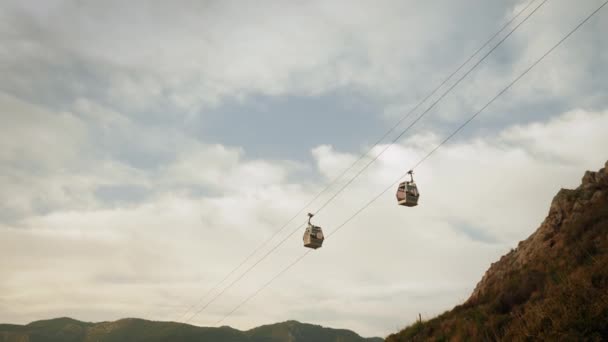 Cabañas de cable modernas que suben y bajan en las montañas contra el cielo gris nublado — Vídeos de Stock