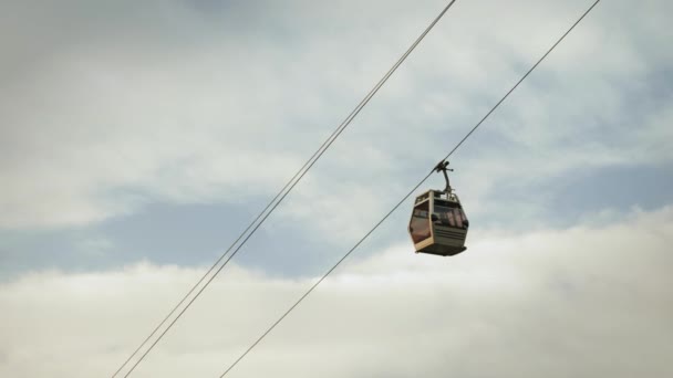 Kabinenbahn fährt gegen grauen bewölkten Himmel hinunter. Bergbahn — Stockvideo