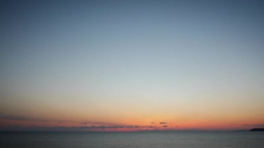 Gün batımında renkli bulutlu bir manzara. Tüylü bulutlu turuncu gökyüzü denizin üzerinde gün batımında