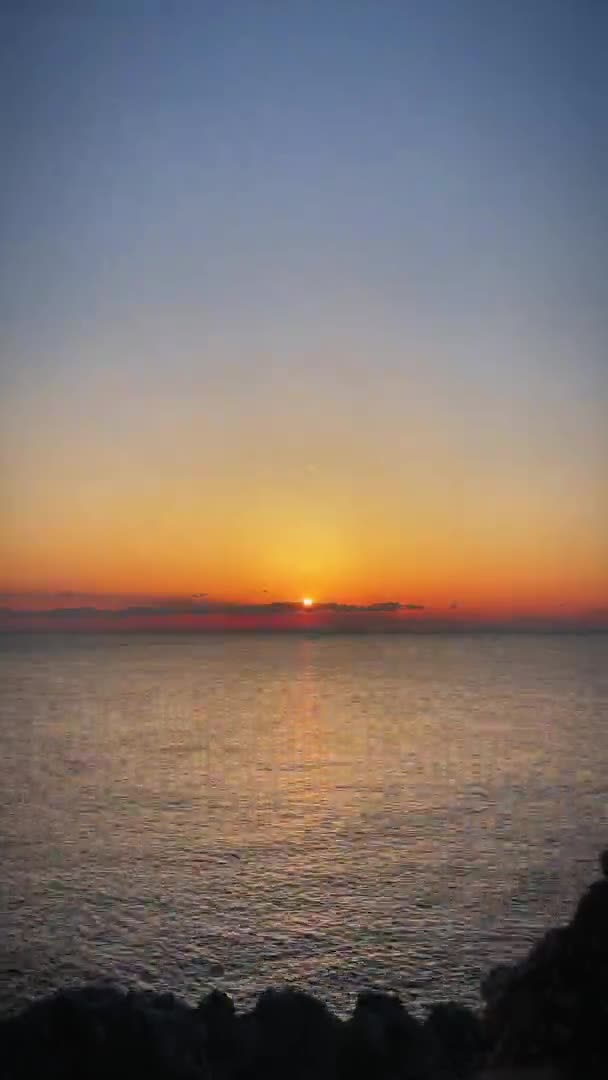 Színes naplemente, függőleges videó. Napnyugta a tengeren drámai narancssárga égbolttal — Stock videók