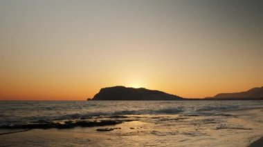 Tropikal günbatımında inanılmaz turuncu gökyüzü ufukta kayalık bir uçurum görünüyor.