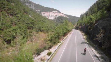 Bisikletçi güzel dağ manzaralı yol boyunca bisiklet sürüyor.