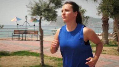 Kumsalda koşmak. Güneşli bir günde dışarıda kardiyo egzersizi yapan bir kadın.