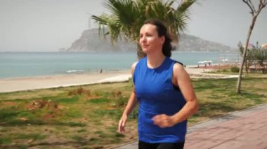 Deniz kıyısında koşan bir kadın. Kadın sabah koşusunda, spor yapıyor.