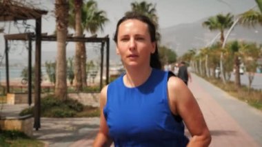 Güneşli bir günde açık havada koşan atletik zinde bir kadın. Gezinti güvertesinde koşan kadın.