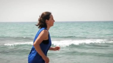 Sağlıklı yaşam tarzı, koşma ve açık hava egzersizleri. Deniz kıyısında koşan bir kadın