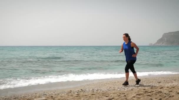 Una donna che corre sulla spiaggia. Esercizio femminile con corsa all'aperto in riva al mare — Video Stock