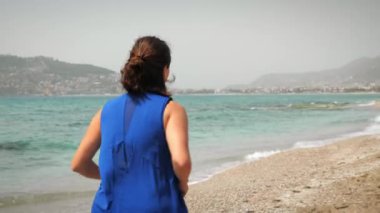Formda atletik bir kadın sabahları koşuyor. Güneşli bir günde sahilde koşan bir kadın.
