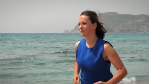 Женщина бегает по пляжу утром. Женщина делает бег тренировки упражнения — стоковое видео