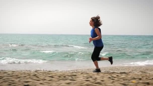Una donna che corre sulla spiaggia, si allena. Corsa femminile vicino al mare. Attività di fitness — Video Stock