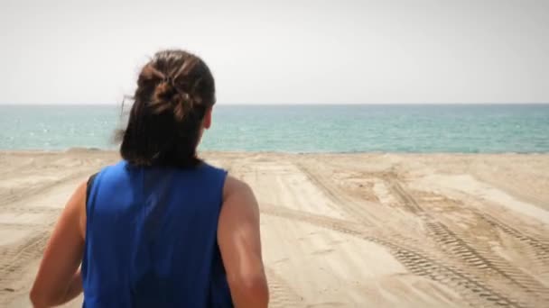 Mulher a correr em direcção ao mar. Corrida feminina na praia no dia ensolarado.Estilo de vida ativo — Vídeo de Stock