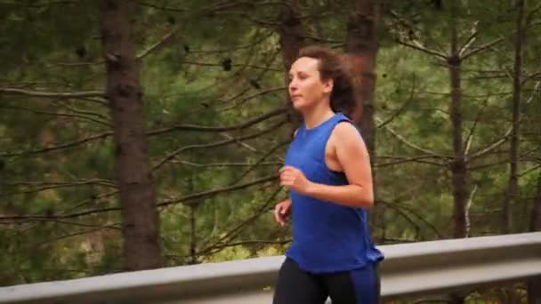 Coupe femme vêtements de sport courir en plein air. Femme sportive jogging sur la route de montagne — Video