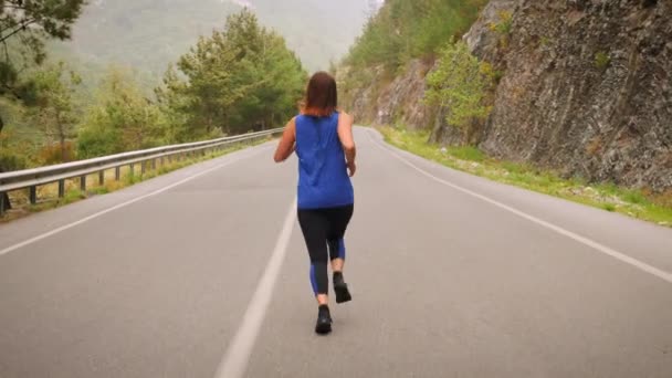 Concepto de funcionamiento. Una mujer corriendo por un camino de montaña vacío por la mañana. Concepto deportivo — Vídeos de Stock