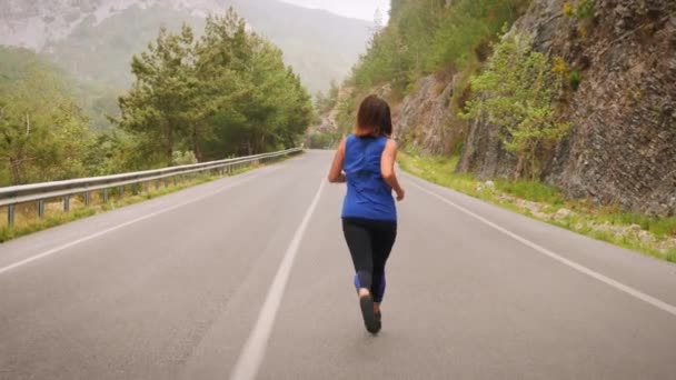 Fiatal sportlány rohangál a szabadban. Női edzés maratoni futás a hegyekben — Stock videók